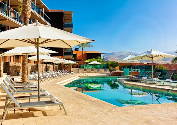 Swimming pool with sun loungers and umbrellas set up around the edge of the pool 