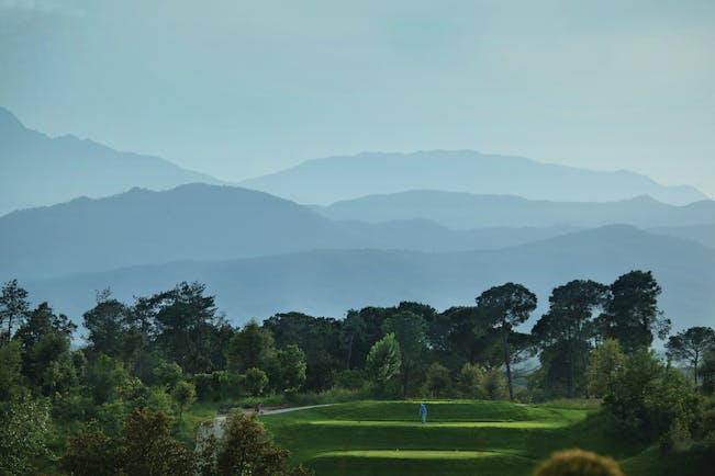 Hotel Camiral golf course, putting green surrounded by trees, mountains in background