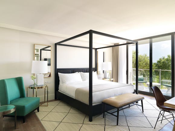 Hotel Camiral junior suite bedroom, four poster bed, armchair, bright modern decor, access to private terrace