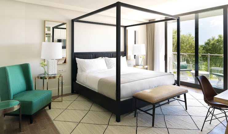 Hotel Camiral junior suite bedroom, four poster bed, armchair, bright modern decor, access to private terrace