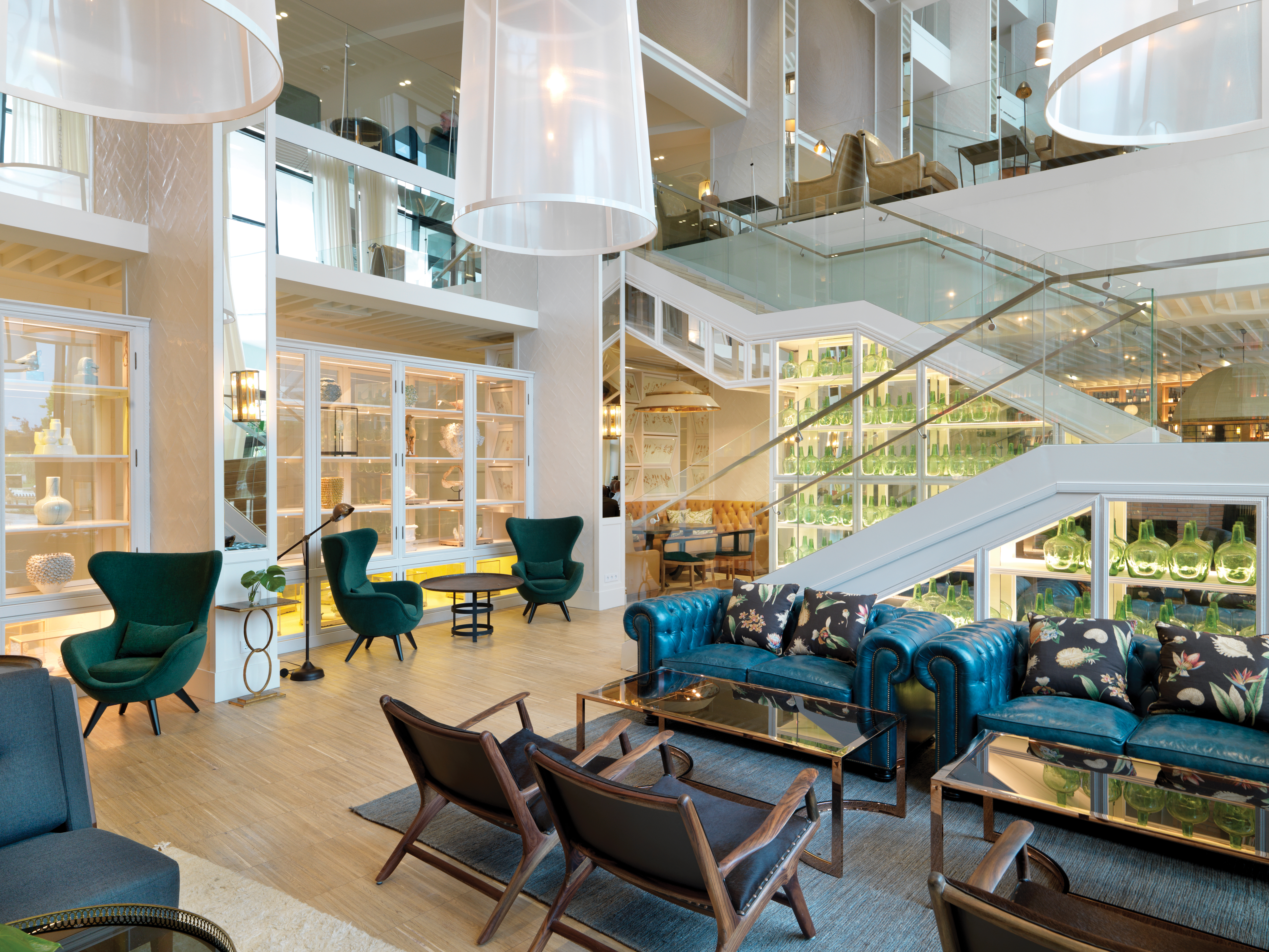 Hotel lobby with modern decor, glass stair cases and sofas and chairs laid out for seating 