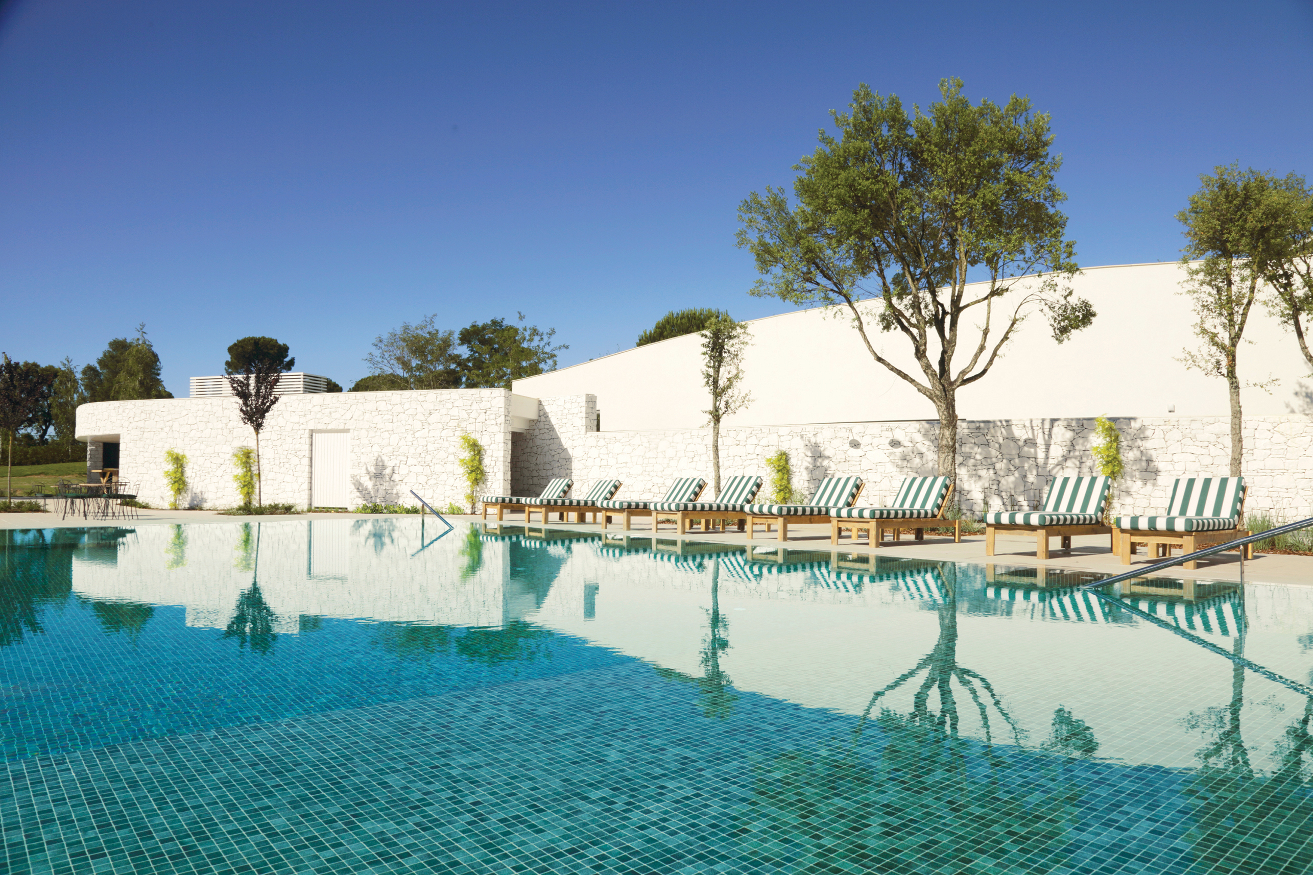 Swimming pool with deck chairs around the outside of pool edge