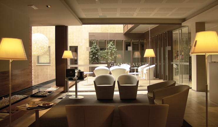 Lobby at the hotel gran claustre with beige arm chairs, modern glass decor and lamps 