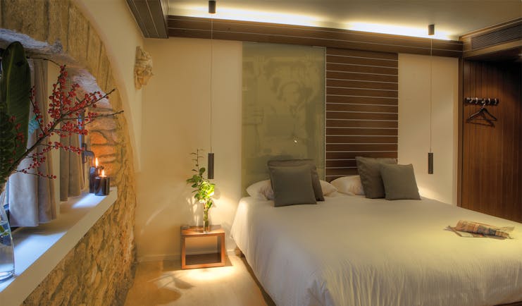 Bedroom with stone walls, candles, large double bed and wardrobe