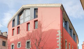 Exterior of hotel with pink and grey building with rectangular windows