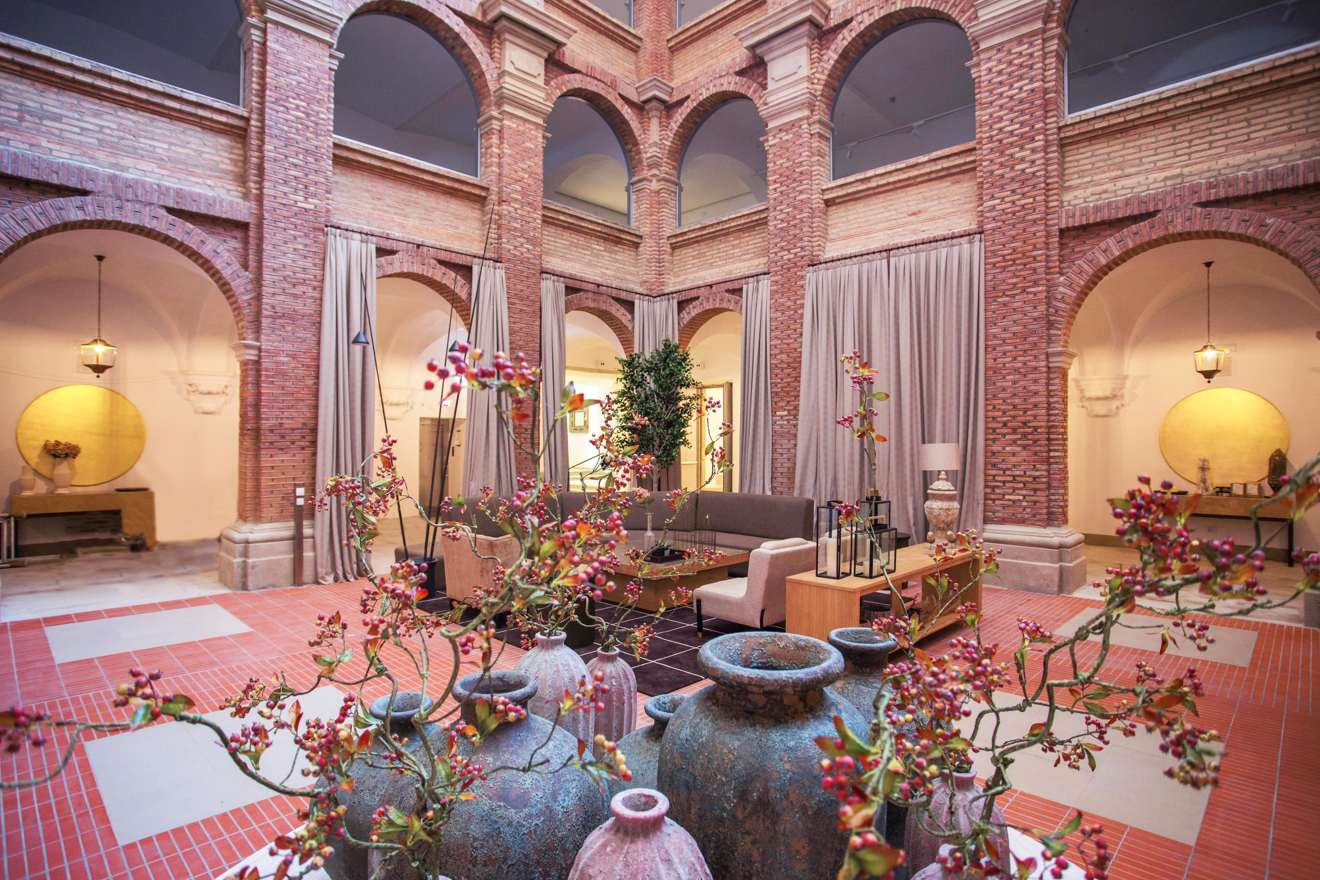 Parador de Lleida lobby, sofas, plants, exposed brick decor, red tiles