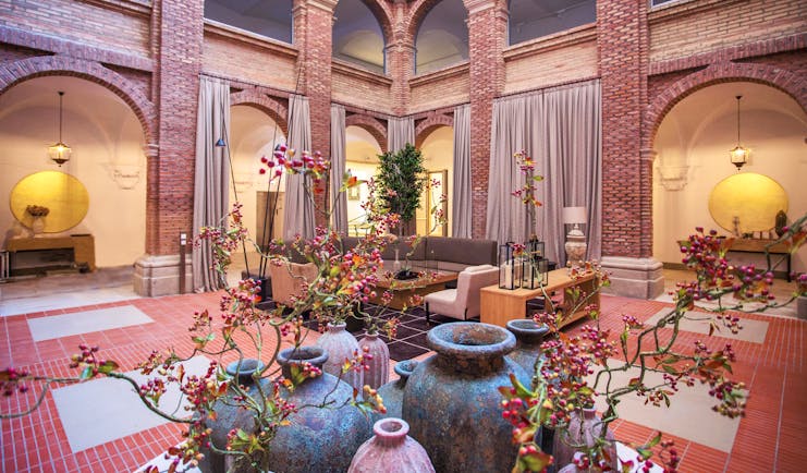 Parador de Lleida lobby, sofas, plants, exposed brick decor, red tiles