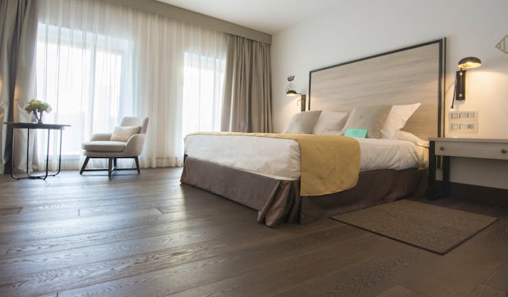 Parador de Lleida standard room, double bed, chair, large windows, pine floors and furniture