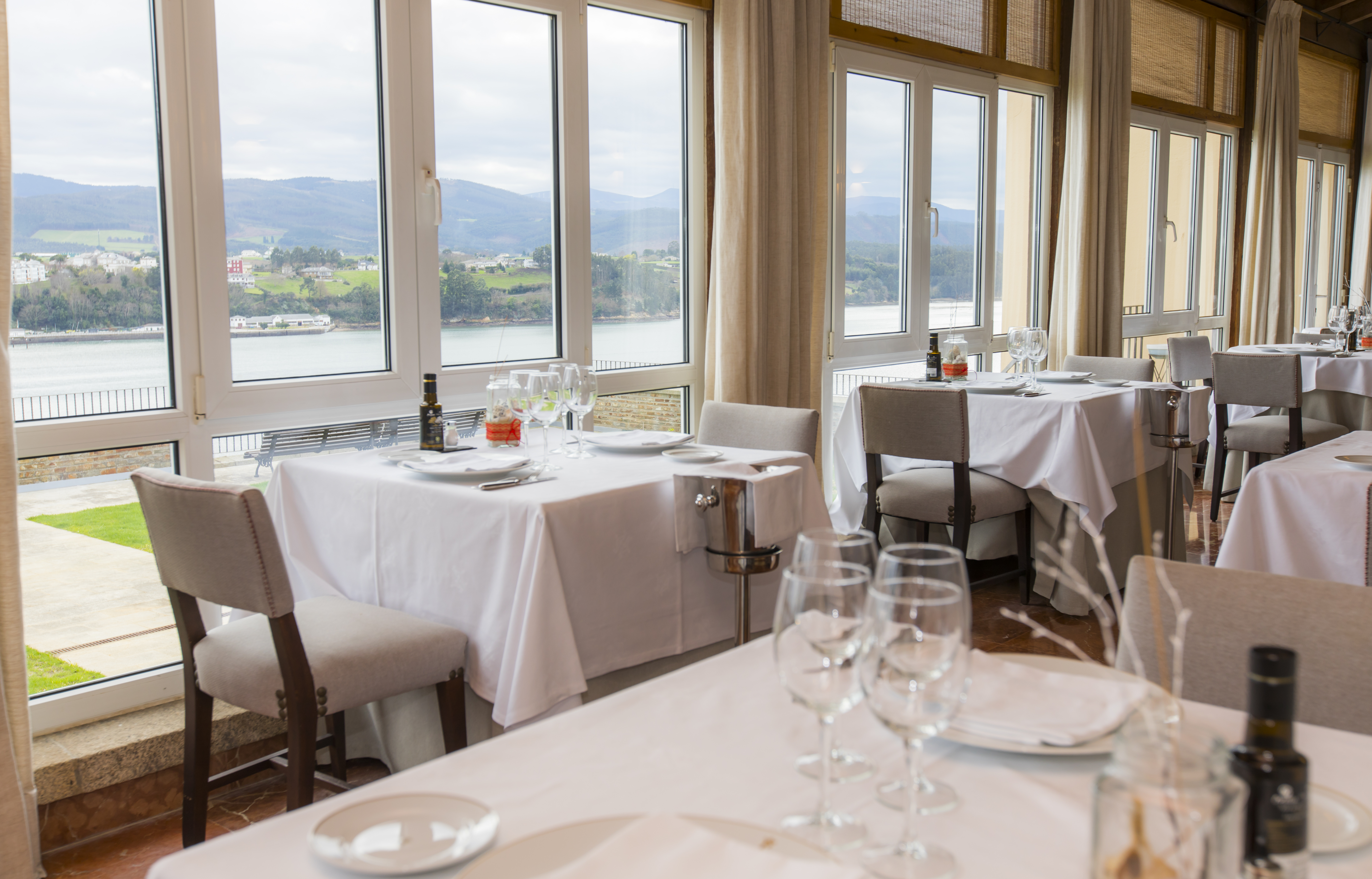 Parador de Ribadeo restaurant, tables, chairs, large windows with views over lake and mountains
