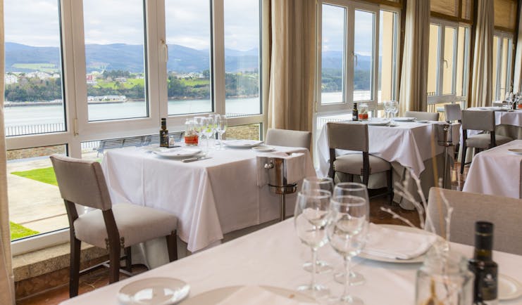 Parador de Ribadeo restaurant, tables, chairs, large windows with views over lake and mountains