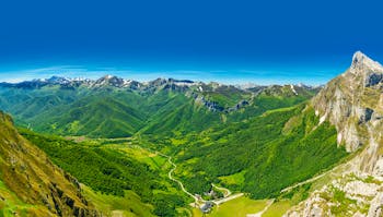 Wooded valley below mountains with snow on tops in the Picos de Europa in Cantabria