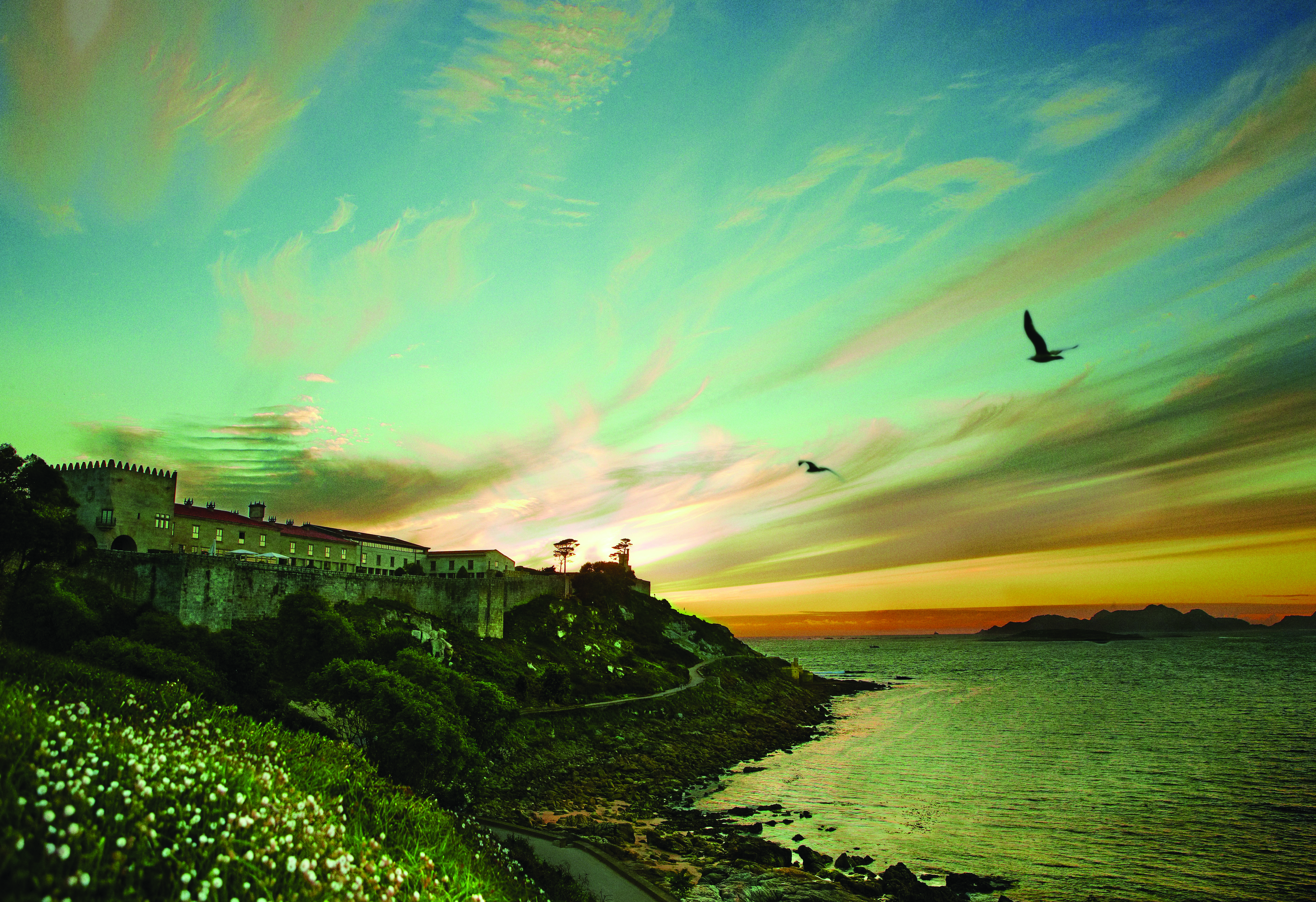 Parador de Baiona Green Spain view of hotel nestled in the cliffside beach in foreground