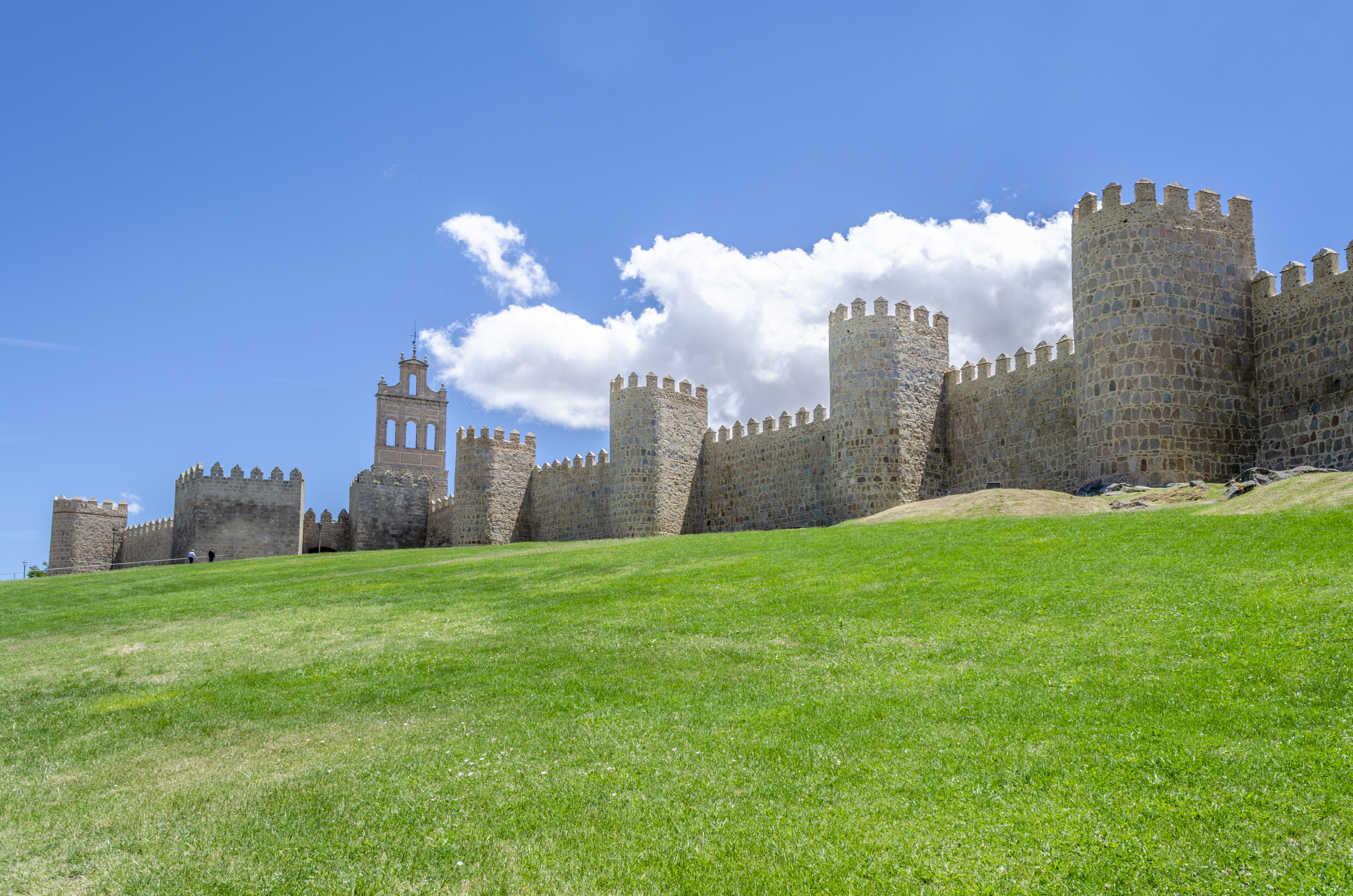 Medieval city wall in grey stone with lots of turrets in town of Avila