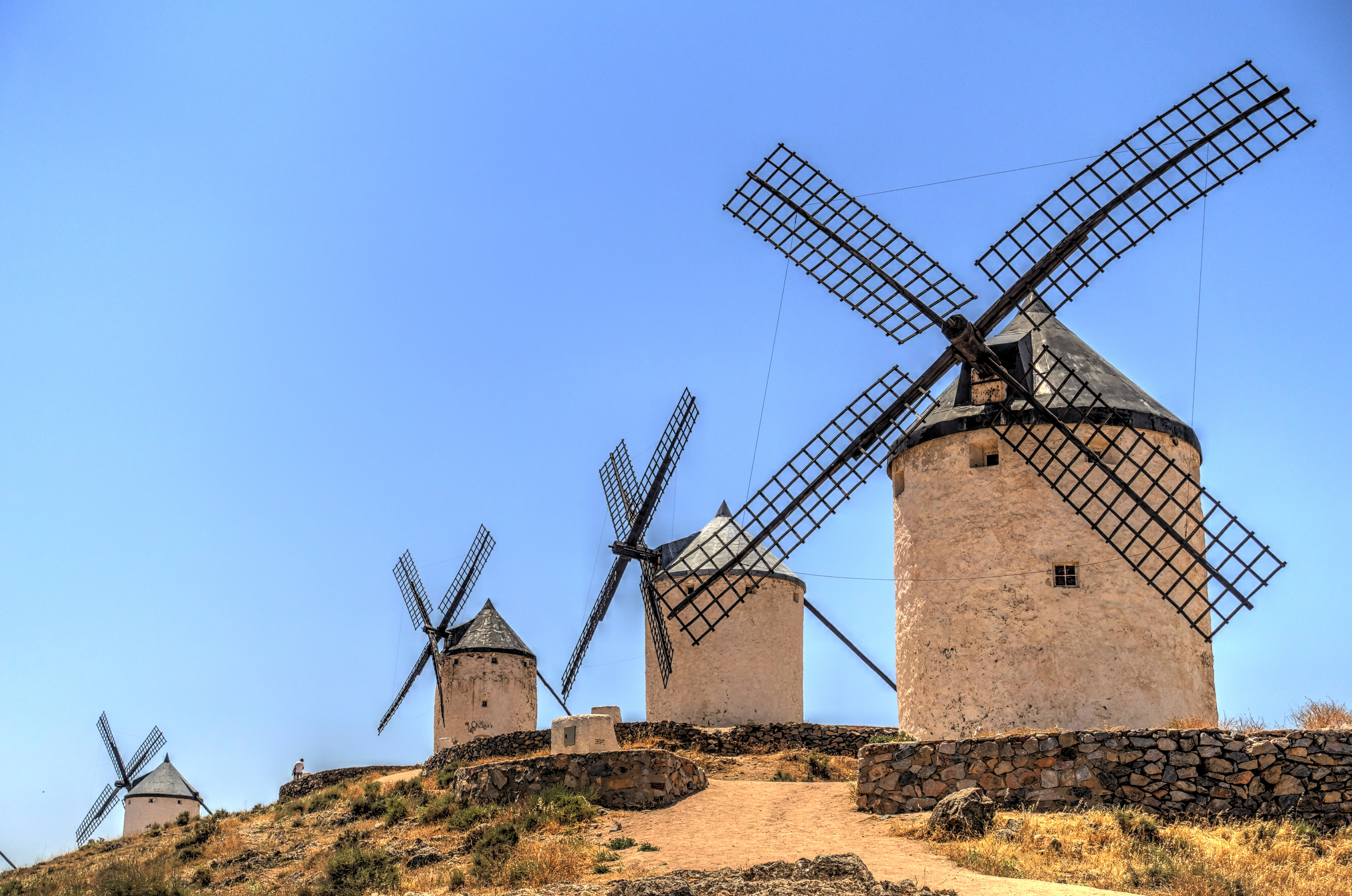 Row of white and black windmills on sandy bank