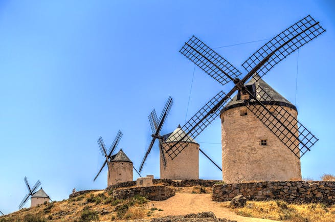 Row of white and black windmills on sandy bank