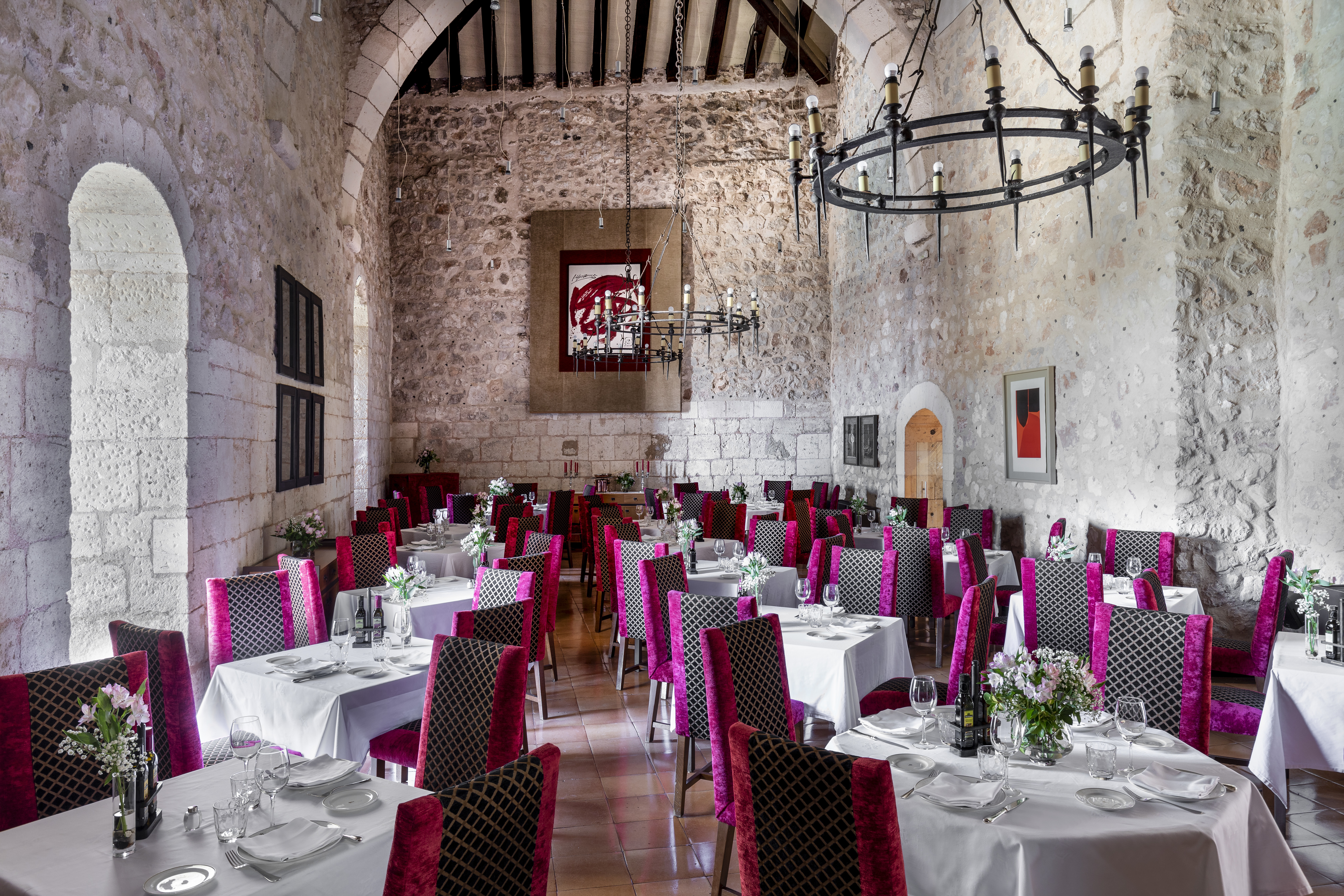 Parador de Alarcon dining hall with stone walls and pink chairs