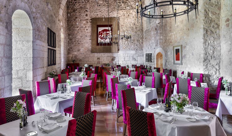 Parador de Alarcon dining hall with stone walls and pink chairs
