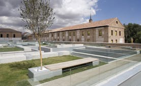 Parador de Alcala de Henares gardens, lawns, trees, hotel buildings, modern garden benches