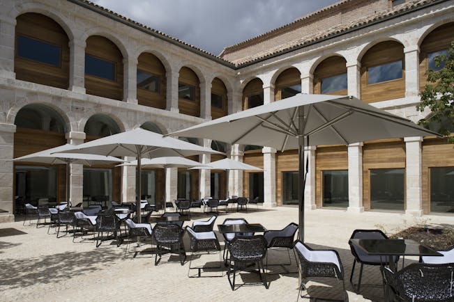 Parador de Alcala de Henares terrace, outdoor seating area, tables and chairs, hotel building
