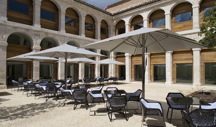 Parador de Alcala de Henares terrace, outdoor seating area, tables and chairs, hotel building