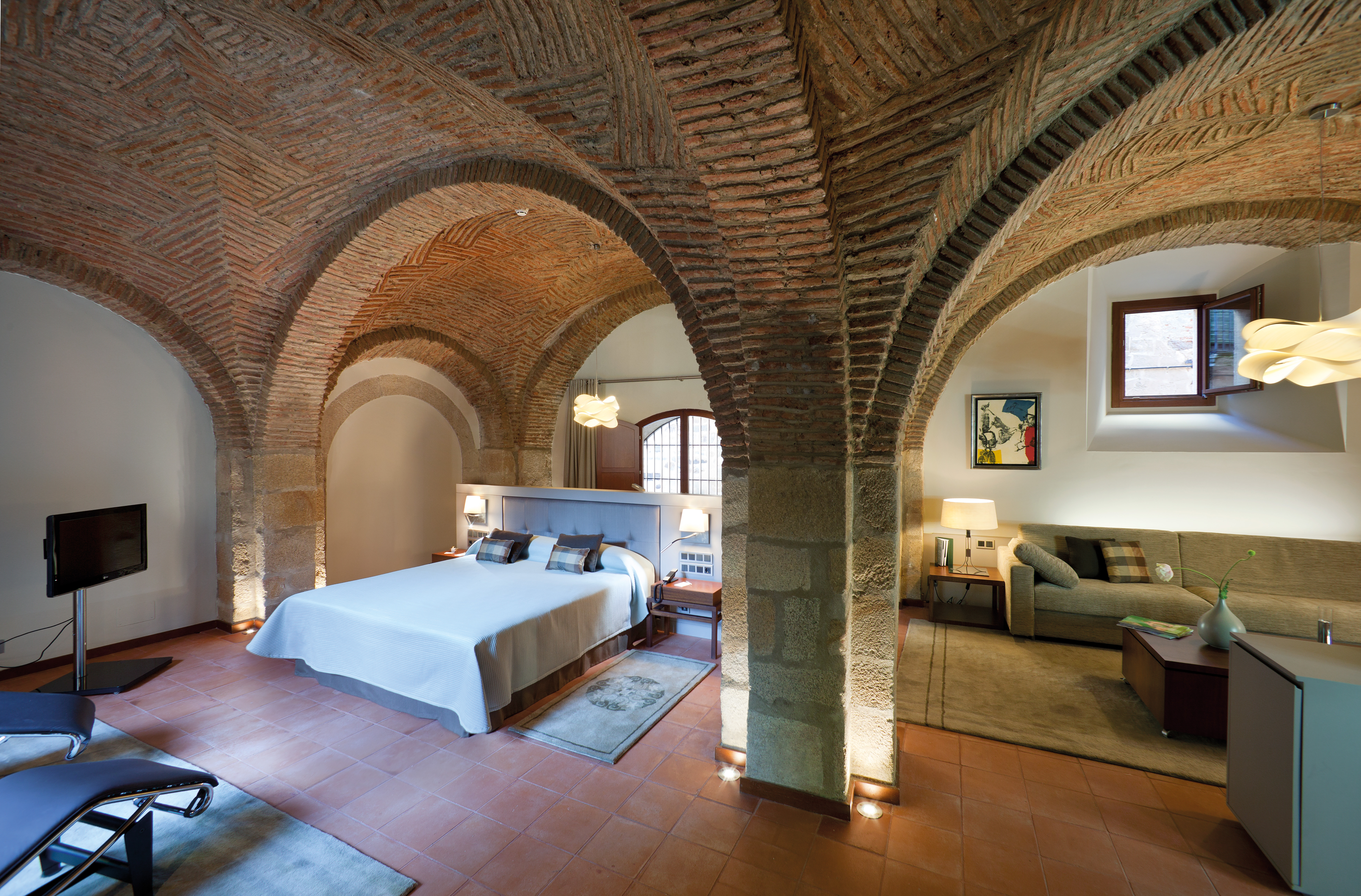 Bedroom with stone walls and archways, large double bed and television