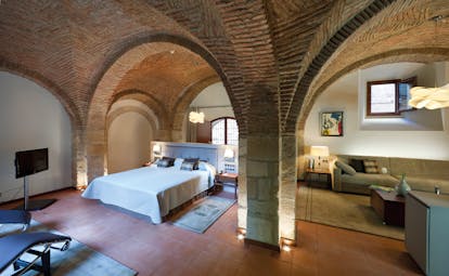 Bedroom with stone walls and archways, large double bed and television