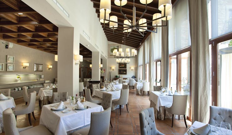 Restaurant area, a light room with window pannelled walls and dining tables and chairs set up inside