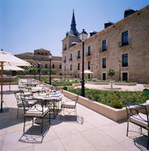 Parador de Lerma terrace, outdoor dinign area, patio, garden beds, hotel building 