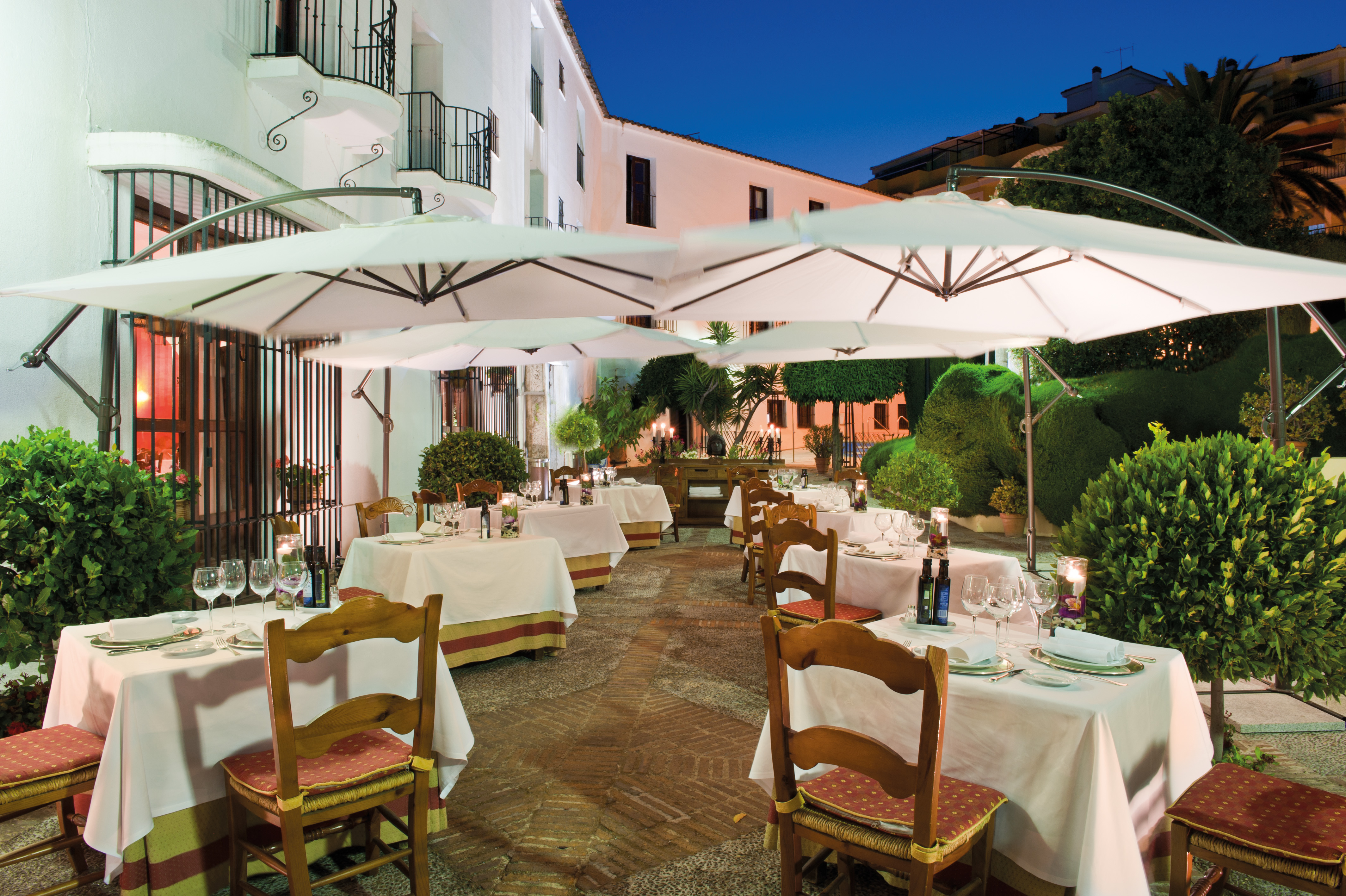 Terrace area with tables and chairs set out and umbrellas above 