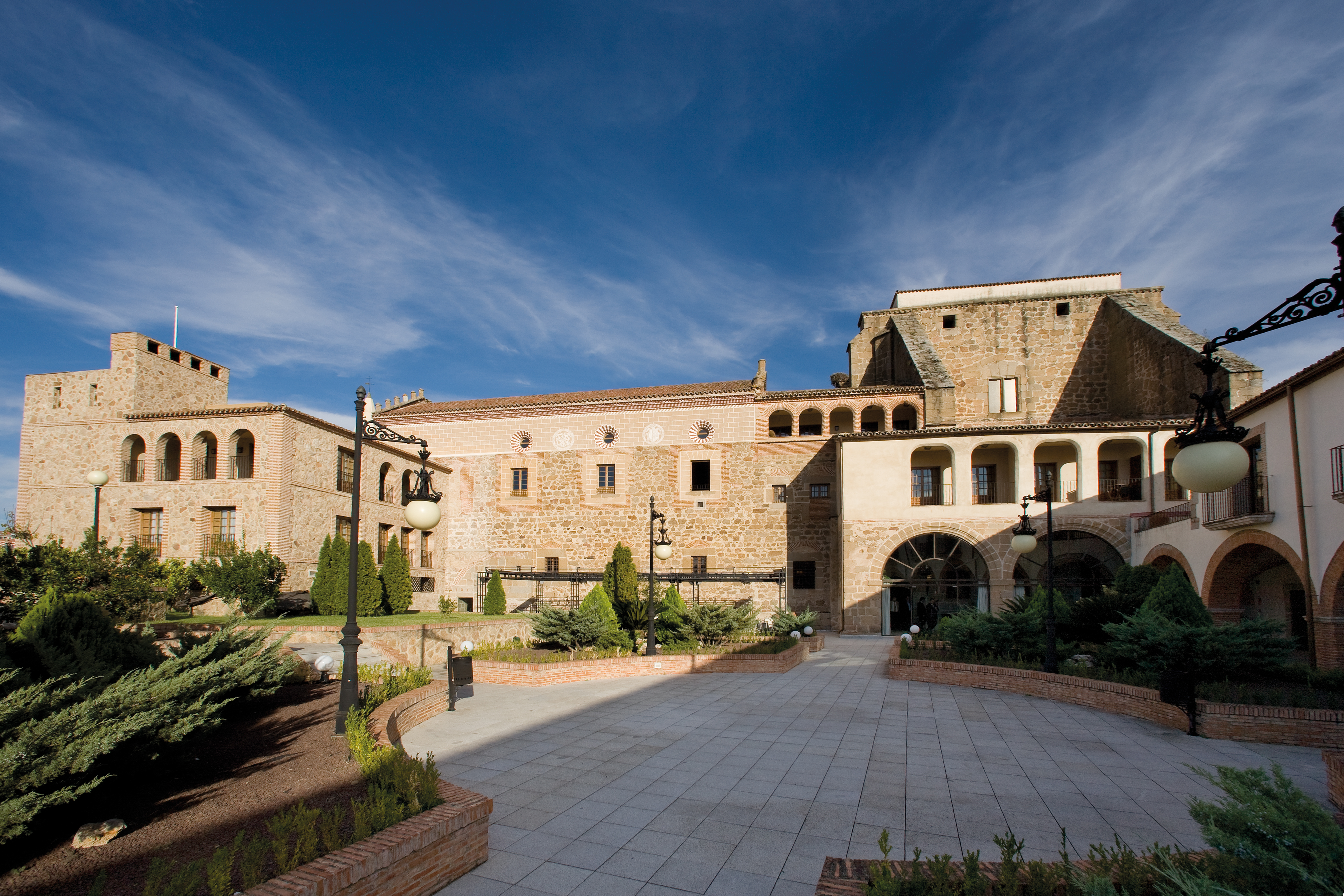 Exterior of hotel, a large stone building with arched windows in and greenery outside