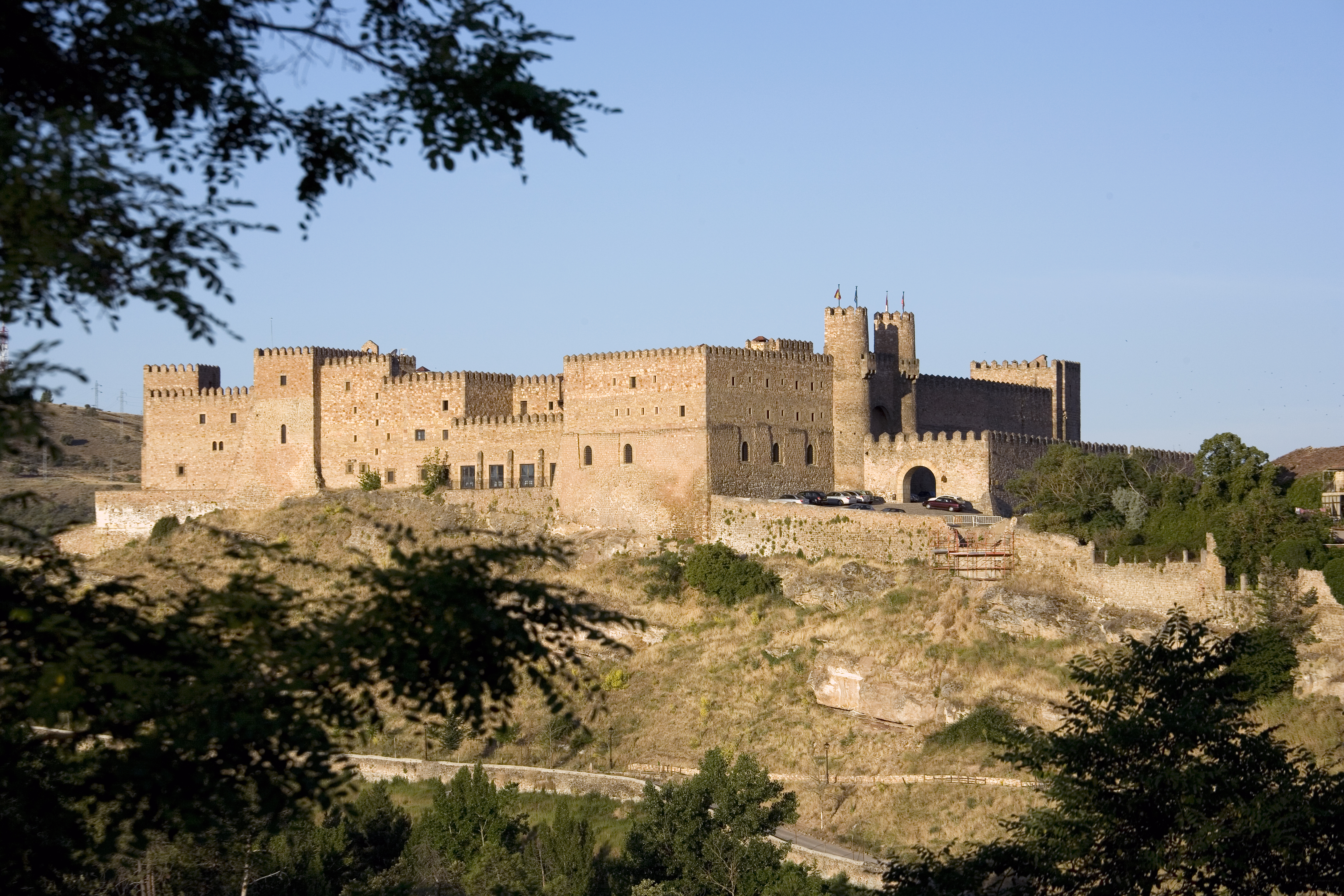 Exterior view of hotel with large castle like building in background on top of grassy mound 