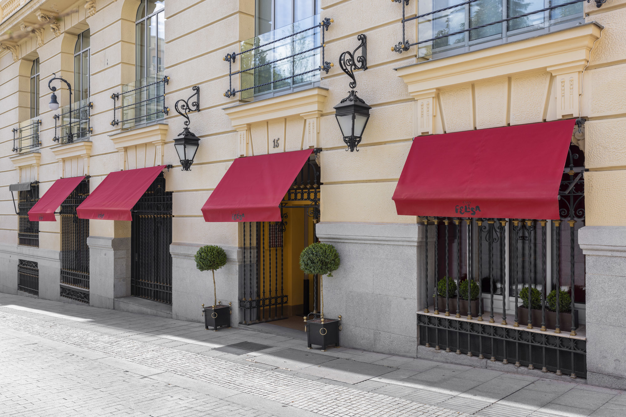 Hotel Urso Casa Felisa Restaurant exterior, with cream-stone walls, wrought iron hanging lanterns, juliet balconies on the uppper windows, and red awnings