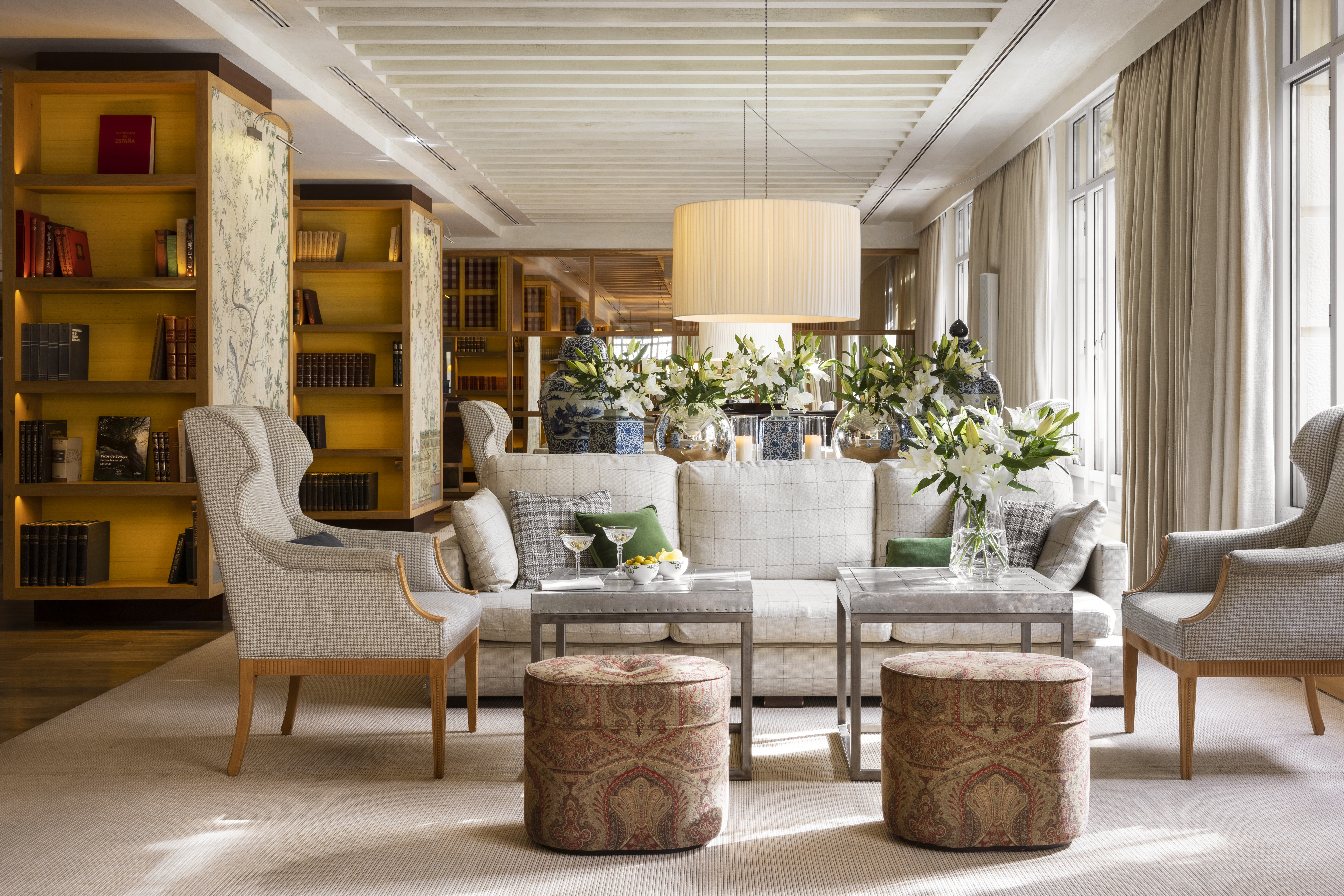Hotel Urso lobby with elegant armchairs and sofas, bookcases, and floor-to-ceiling windows