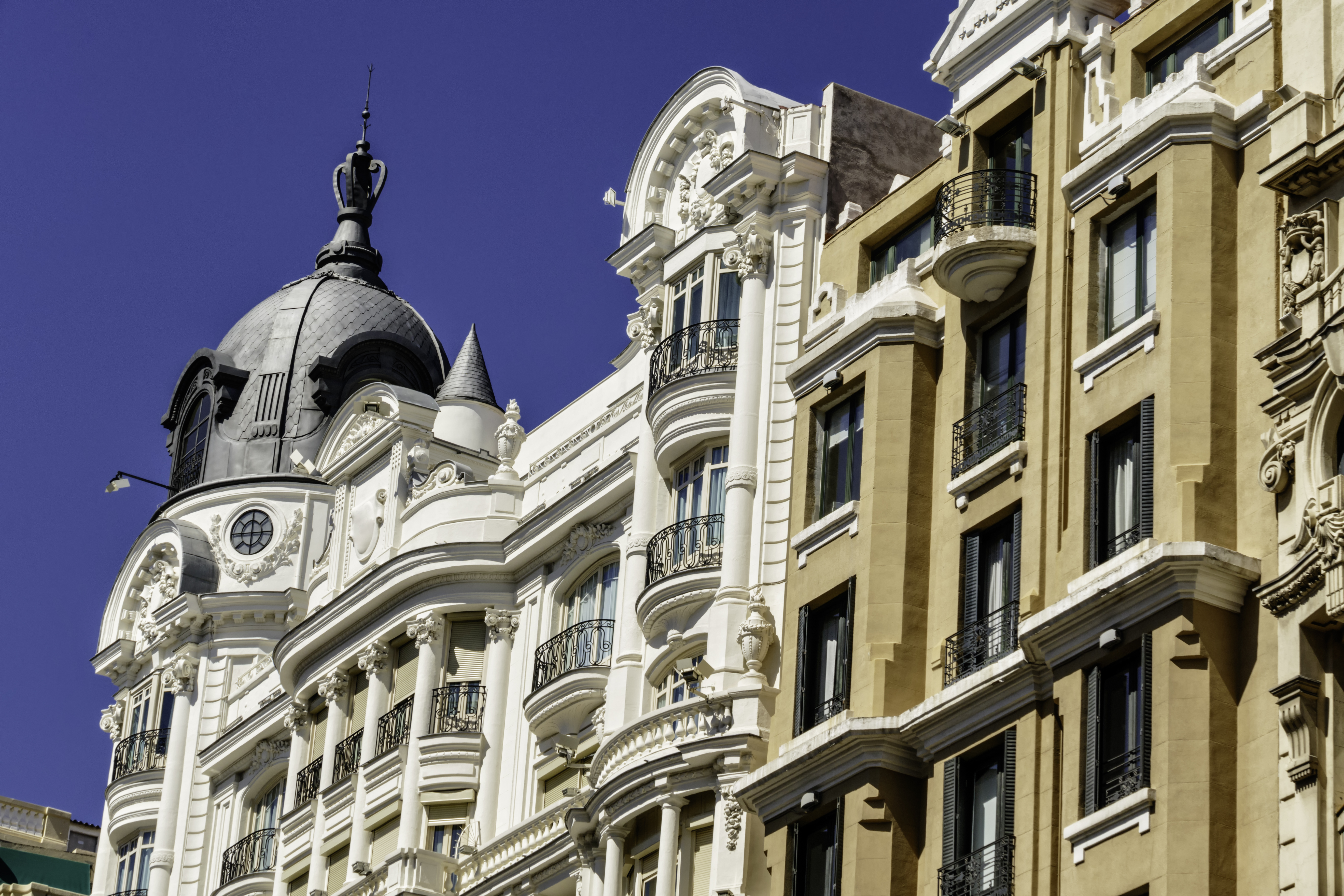 Tall 19th century houses white and yellow with balconies in La Gran Via in Madrid