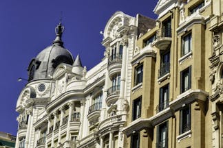 Tall 19th century houses white and yellow with balconies in La Gran Via in Madrid