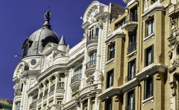 Tall 19th century houses white and yellow with balconies in La Gran Via in Madrid