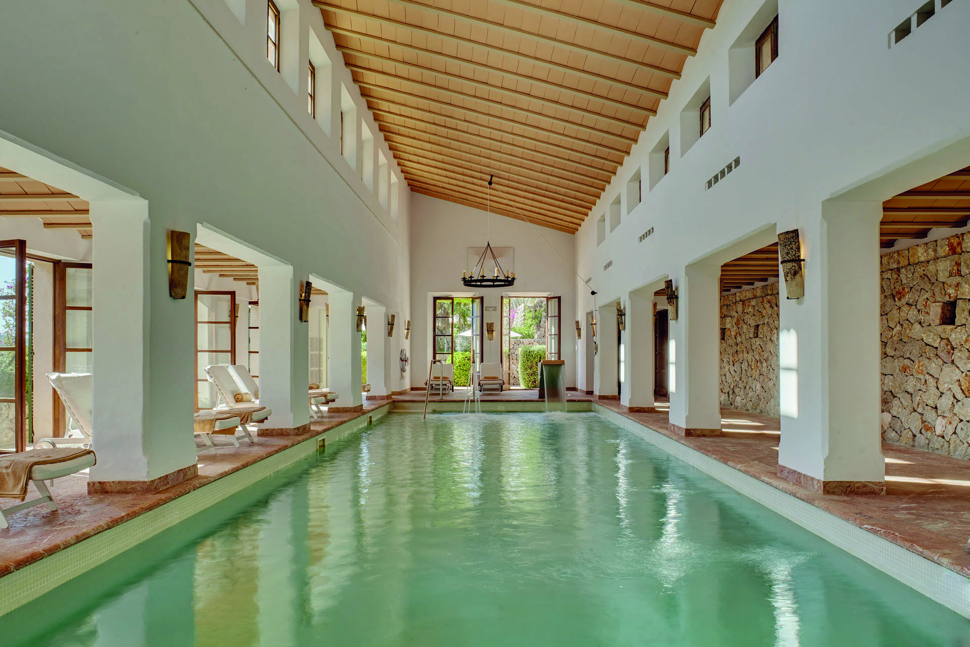 La Residencia Mallorca indoor pool loungers exposed stone walls columns chandeliers