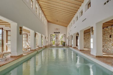 La Residencia Mallorca indoor pool loungers exposed stone walls columns chandeliers