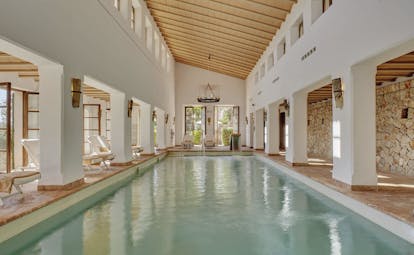 La Residencia Mallorca indoor pool loungers exposed stone walls columns chandeliers