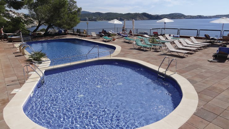Cala Fornells Mallorca pool sun loungers umbrellas sea in background