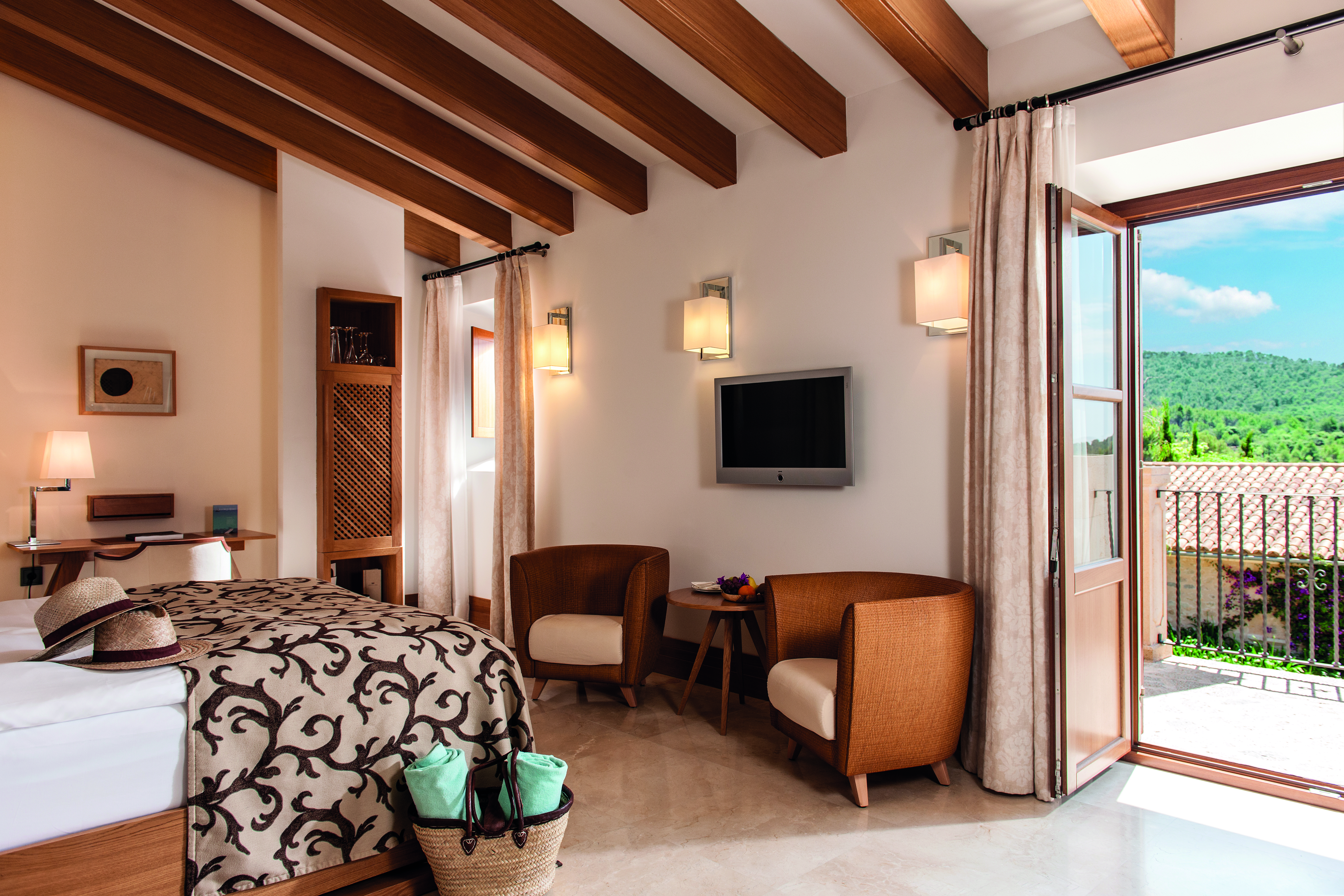 Castell Son Claret Mallorca terrace deluxe suite bed armchairs terrace modern décor