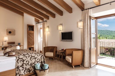 Castell Son Claret Mallorca terrace deluxe suite bed armchairs terrace modern décor
