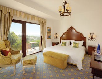 Classic double room with yellow colour scheme, double bed and doors opening onto a balcony