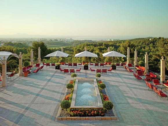 Main terrace with fountain, seating areas and umbrellas looking out over greenery 