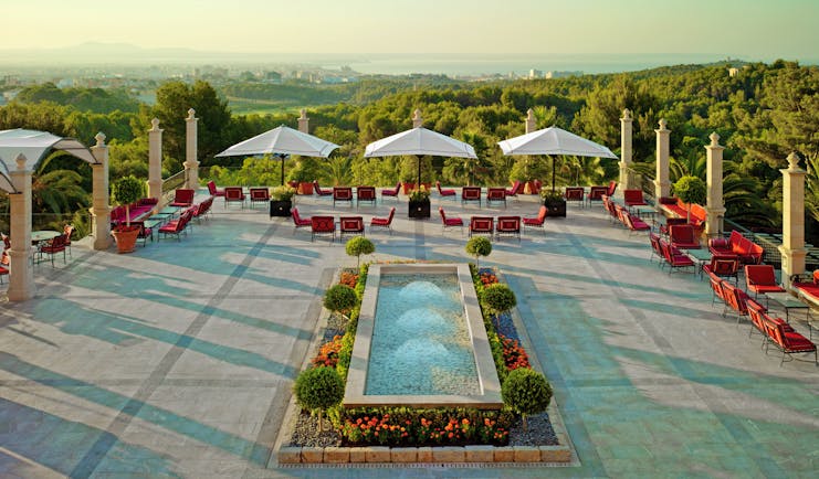 Main terrace with fountain, seating areas and umbrellas looking out over greenery 