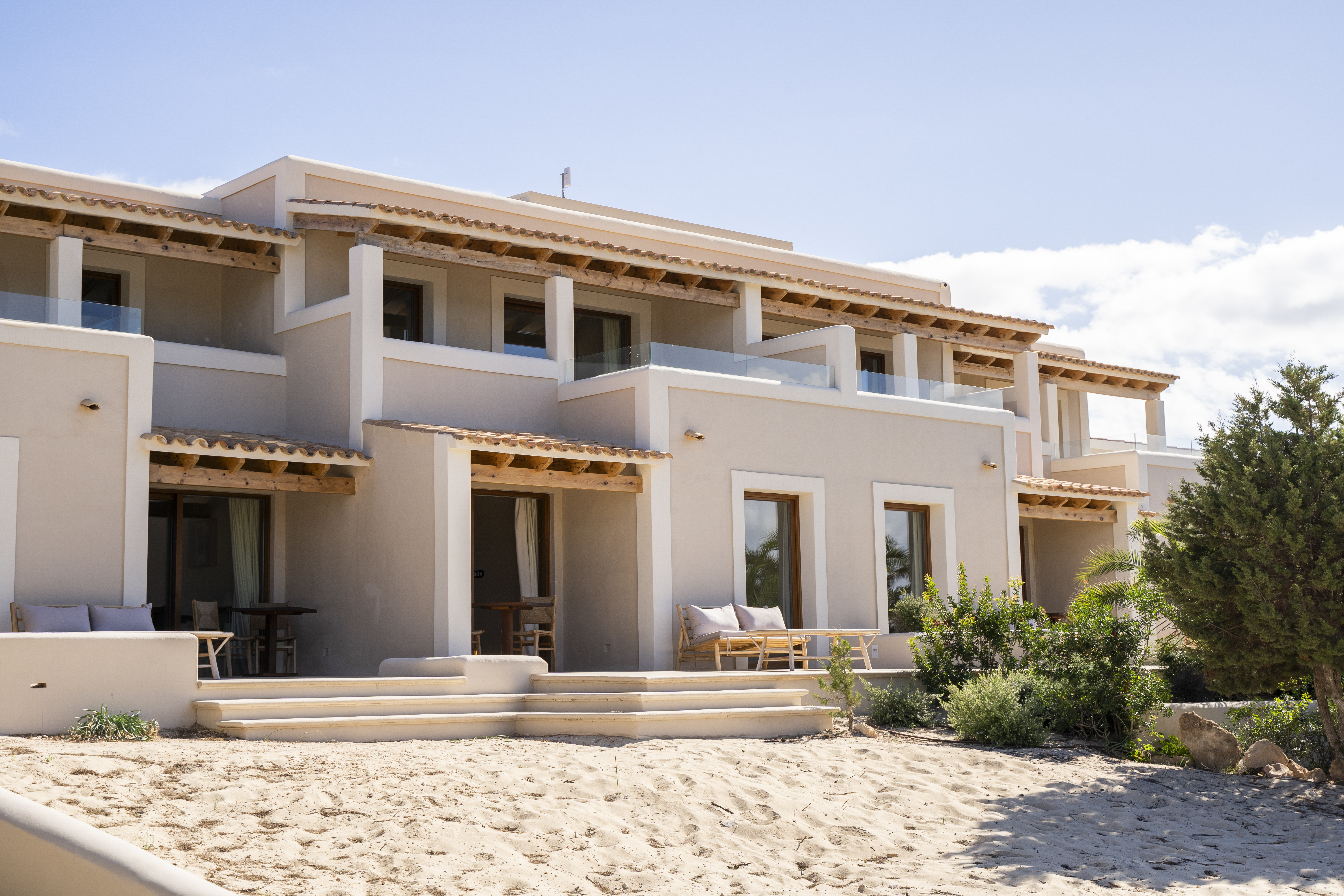 Dunas de Formentera exterior shot, showing off-white walls, wooden shades over terraces and balconies, and sand leaving up to the doors