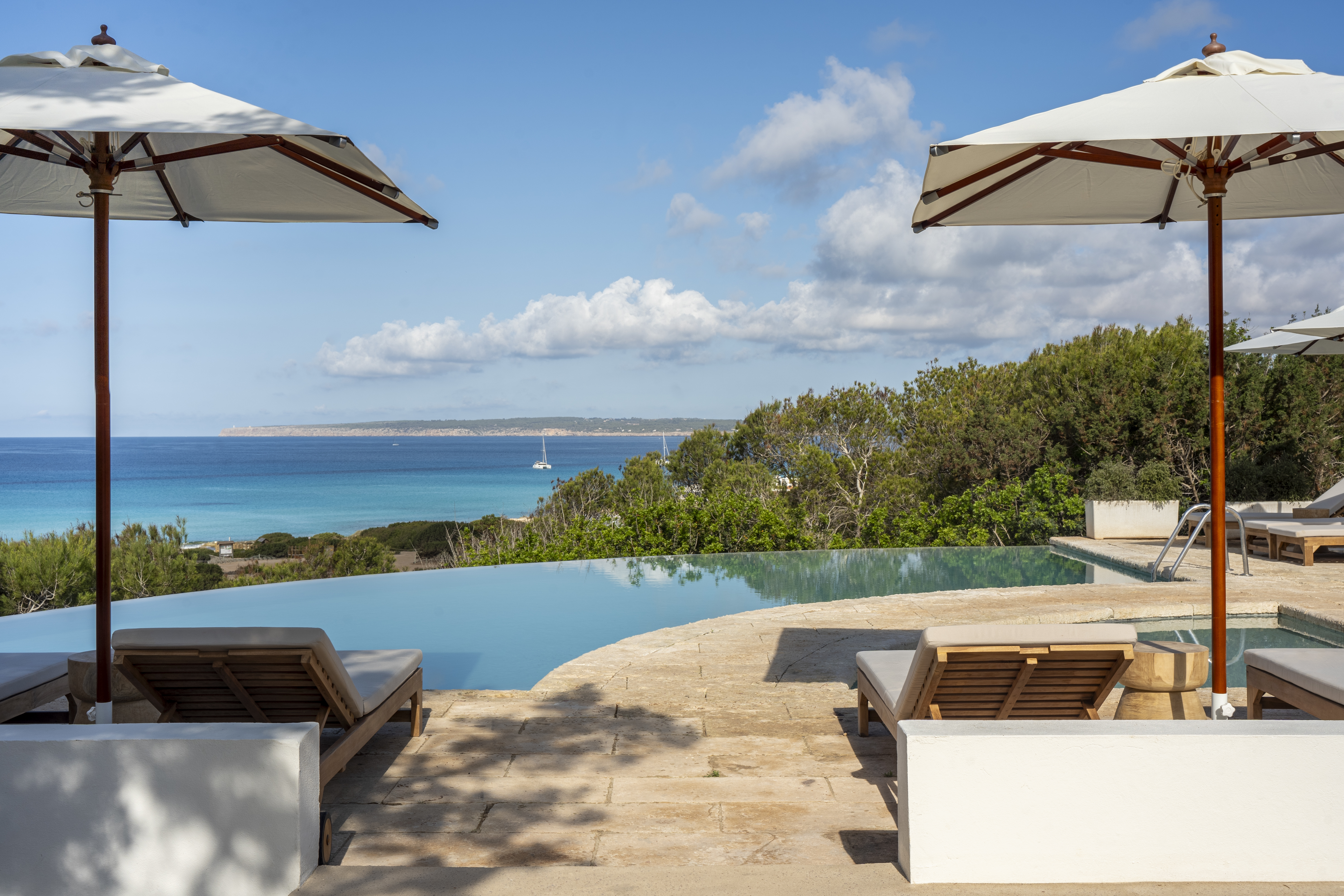 Dunas de Formentera curved infinity swimming pool, with parasols and loungers, and the sea in the distance