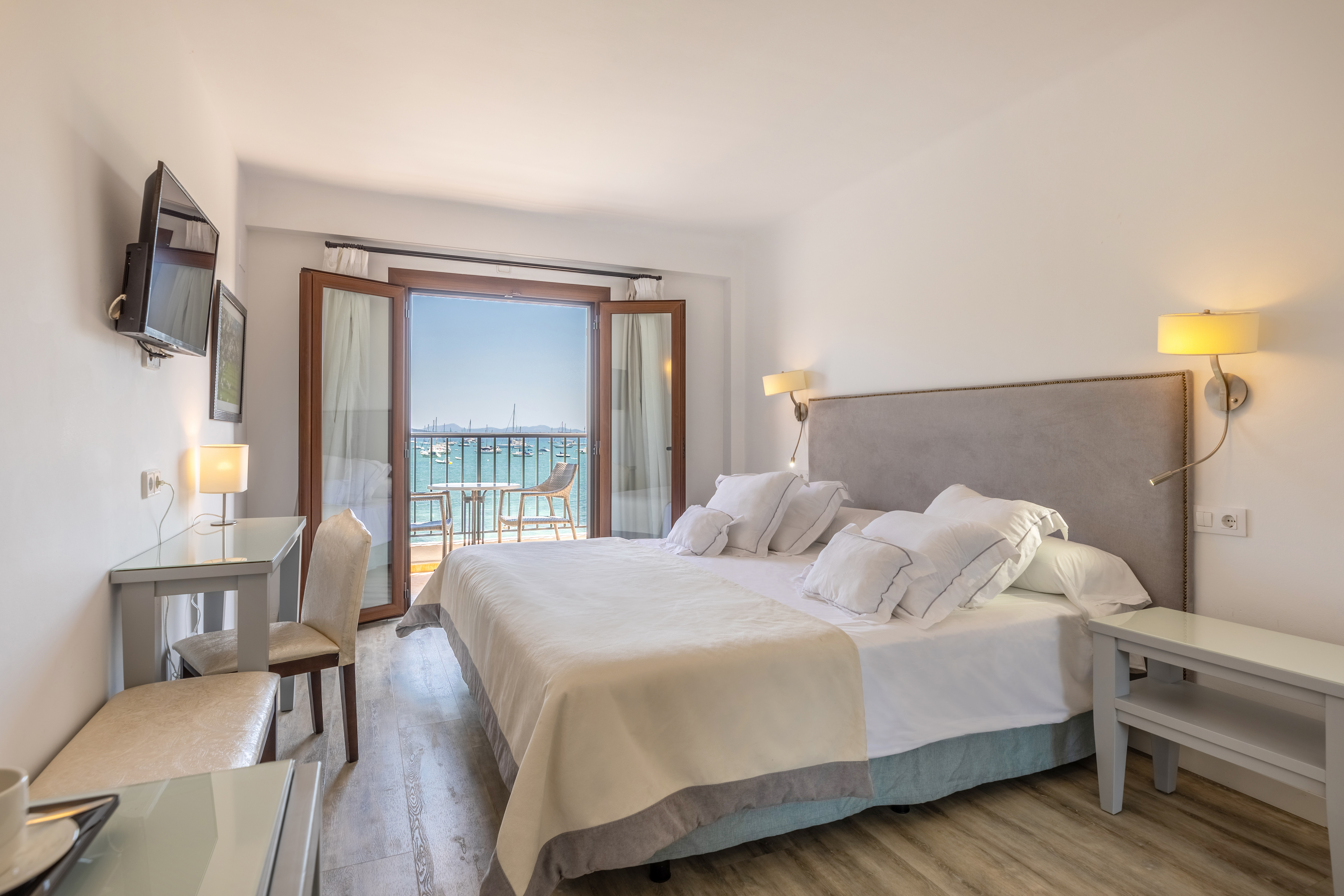 Hotel Hoposa Bahia Sea View Room with bright neutral colours and double doors opening onto a bright blue sea view