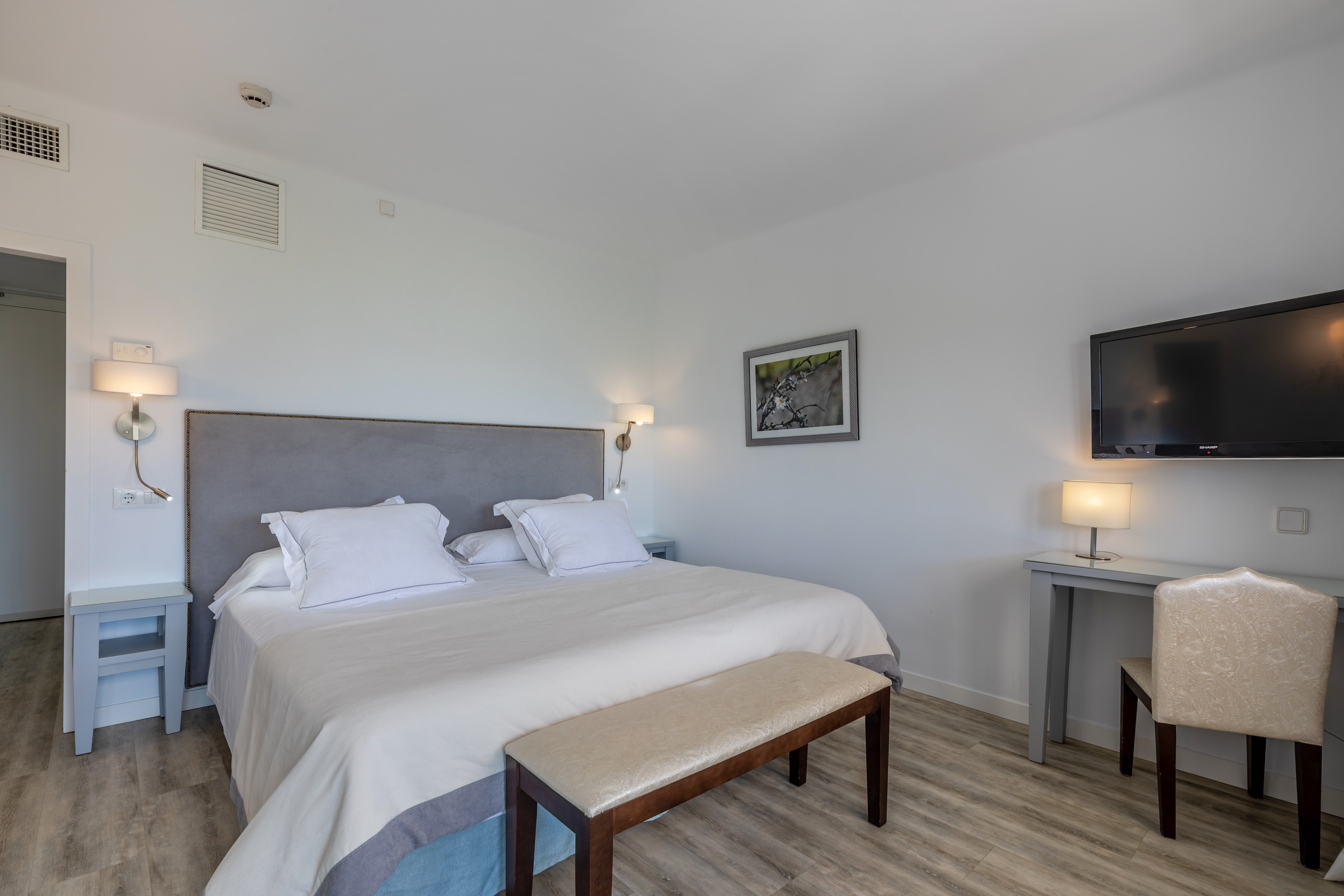 Hotel Hoposa Bahia Standard Room with bright, cool, neutral colour scheme, double bed and desk visible in the right