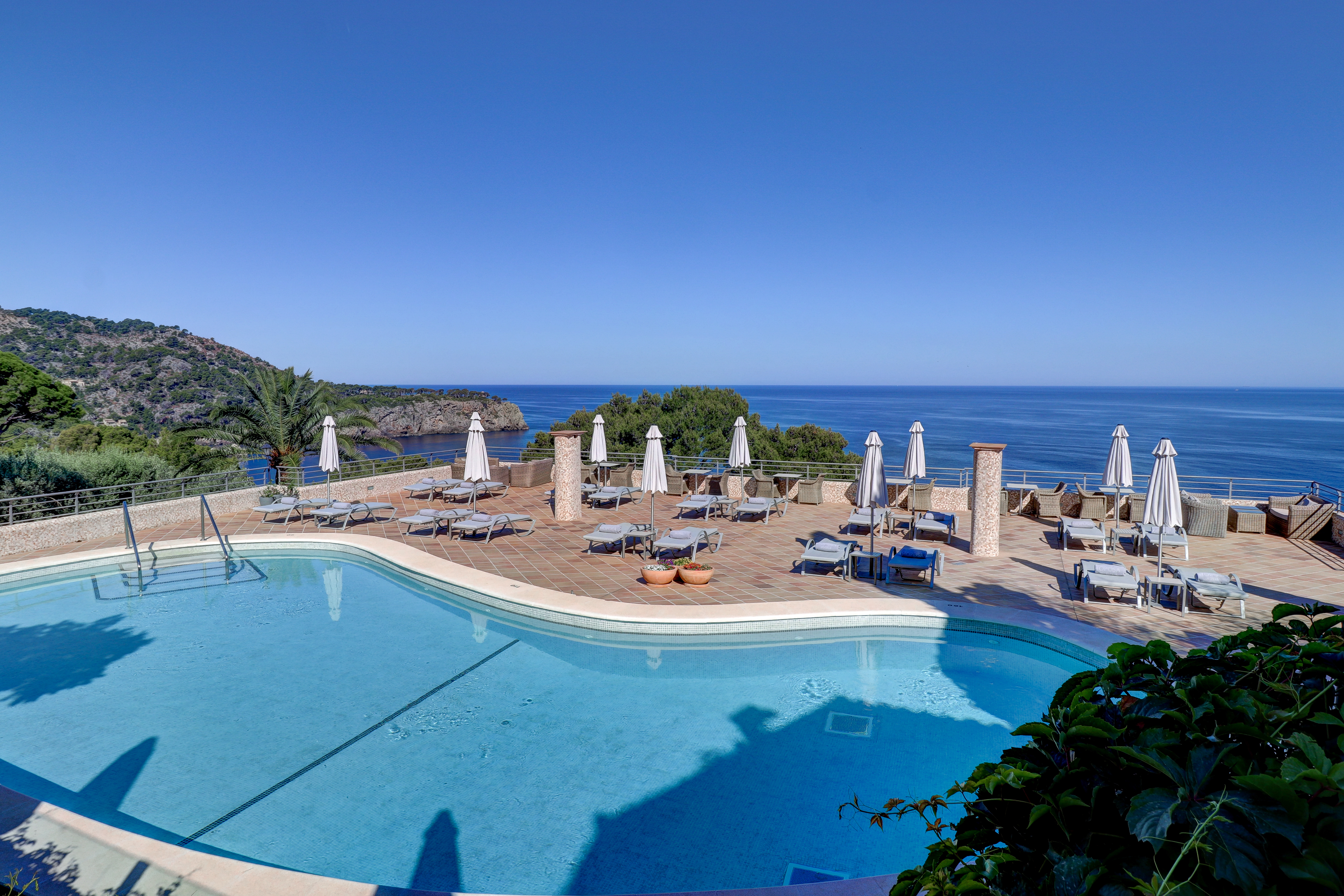 Hotel Hoposa Costa d'Or swimming pool terrace, with freeform pool, sun loungers and parasols, and panoramic views of the sea